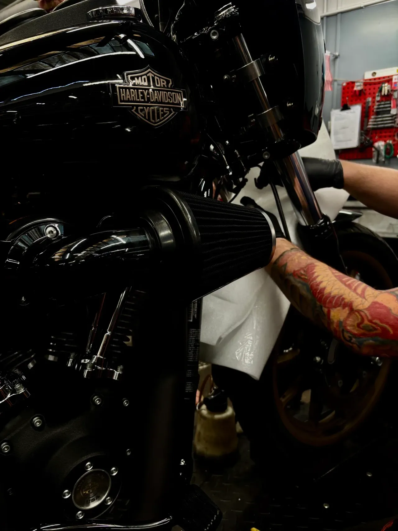 Wytatuowana ręka mechanika pracująca przy filtrze powietrza motocykla