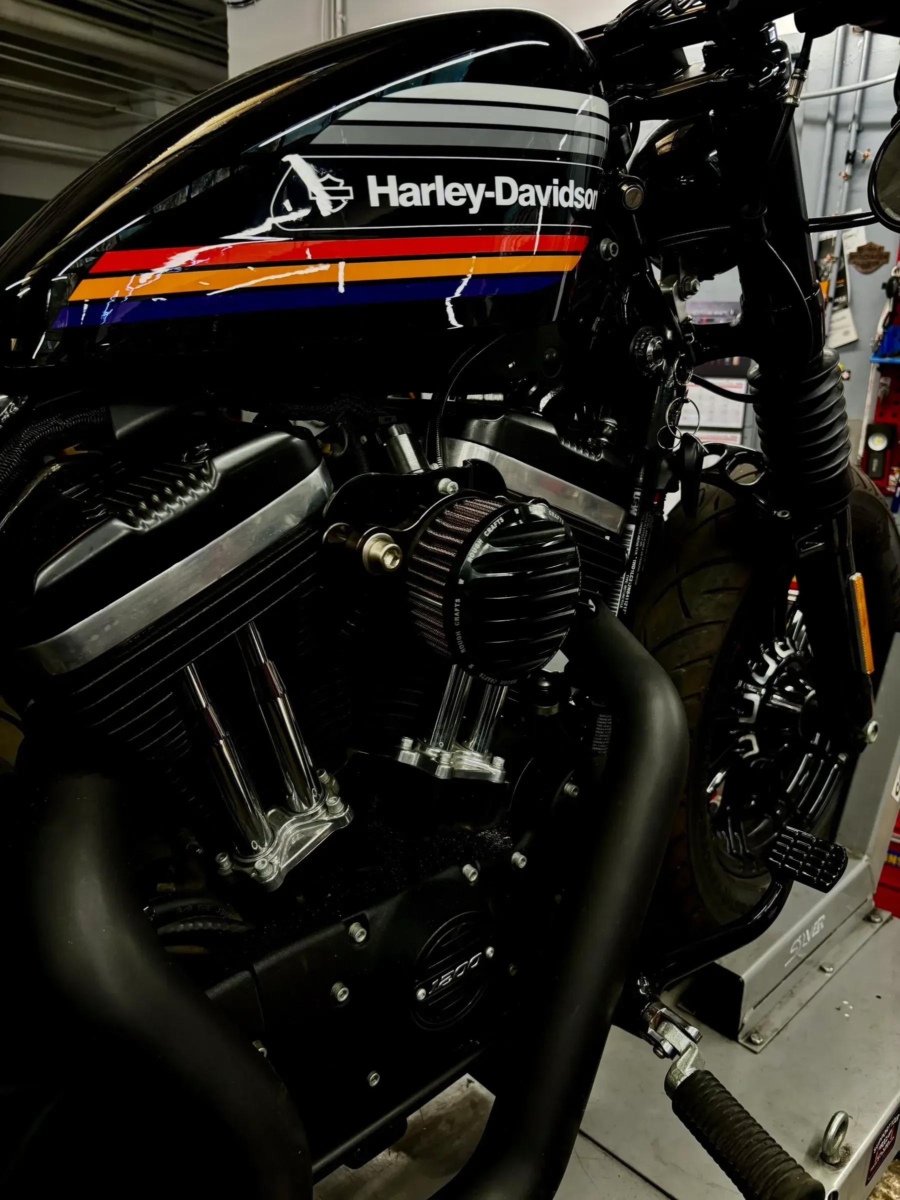 Motocykl na podnośniku, widoczne paski na zbiorniku i odsłonięty silnik