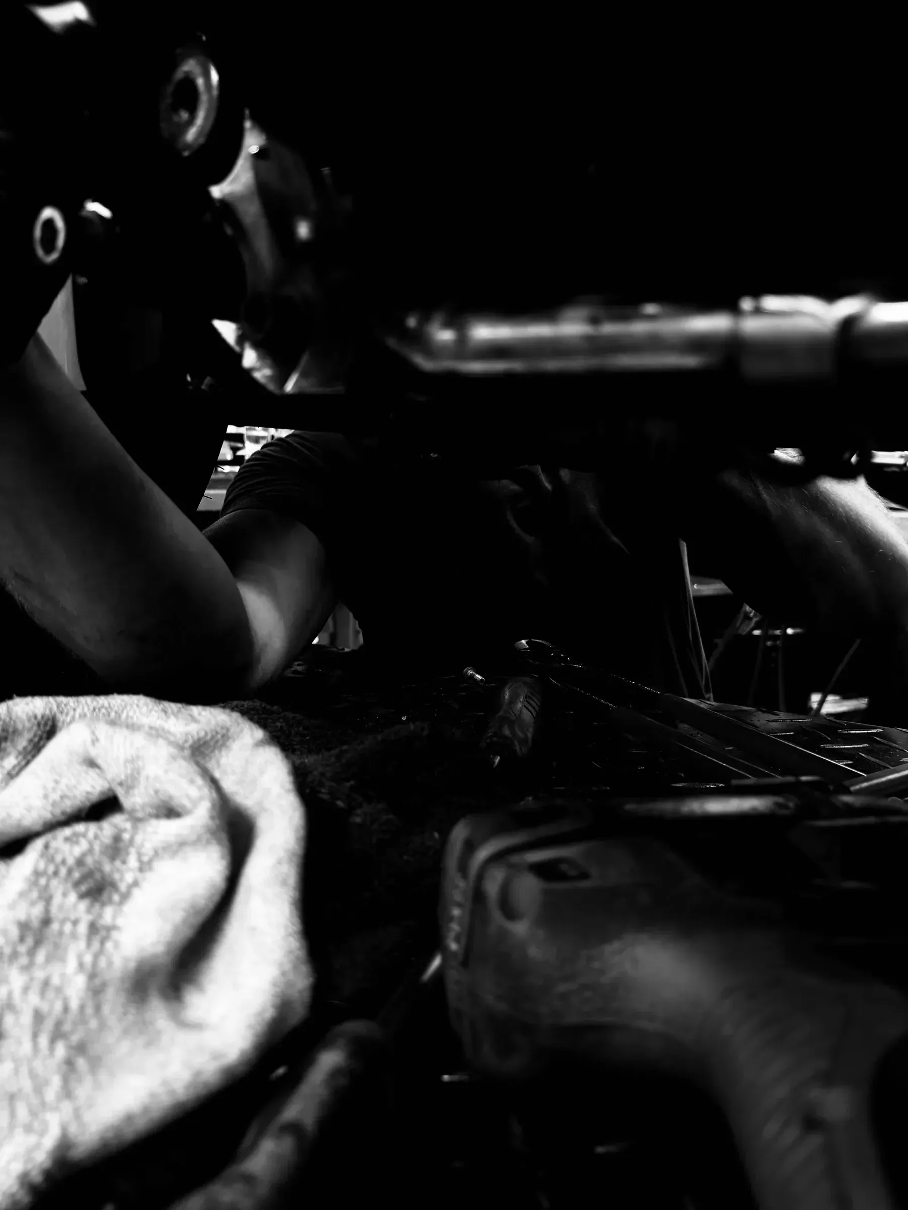 Ręce mechanika pracujące przy silniku motocykla, w dłoni szmatka warsztatowa